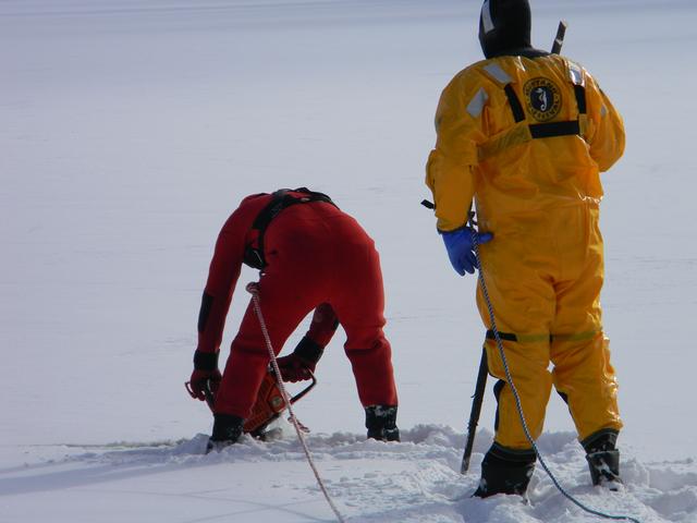 2nd Lieutenant Wassil and FF J Cobb cutting a hole in the ice