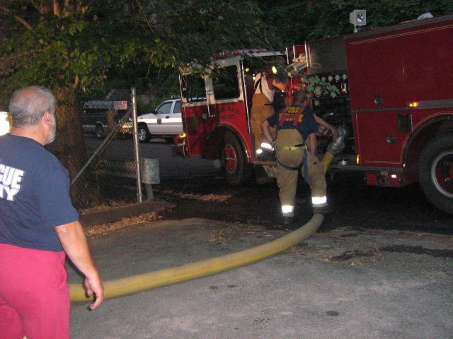 Deputy Chief Koenig connects the supply line to 24-4-2 to refill his tank as Company Engineer Proetta looks on